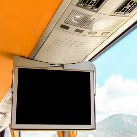 a TV monitor hanging above a charter bus seat