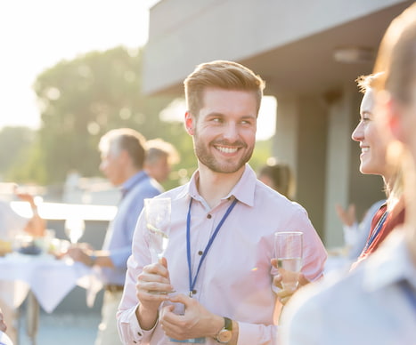 attendees at a corporate event smile while holding drinks