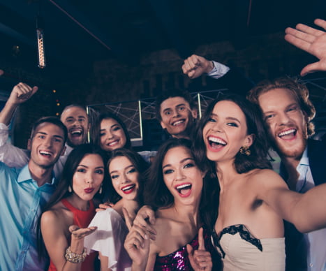 a prom group smiles for a selfie while wearing formal attire